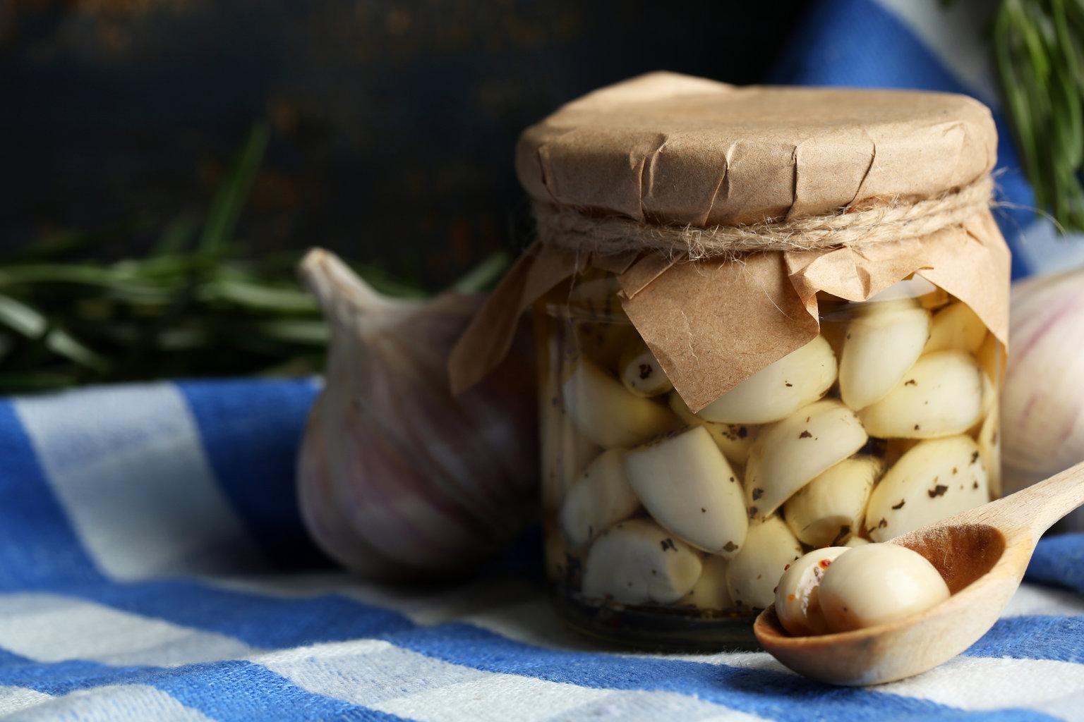 Canned garlic in glass jar and wicker mat and rosemary branches